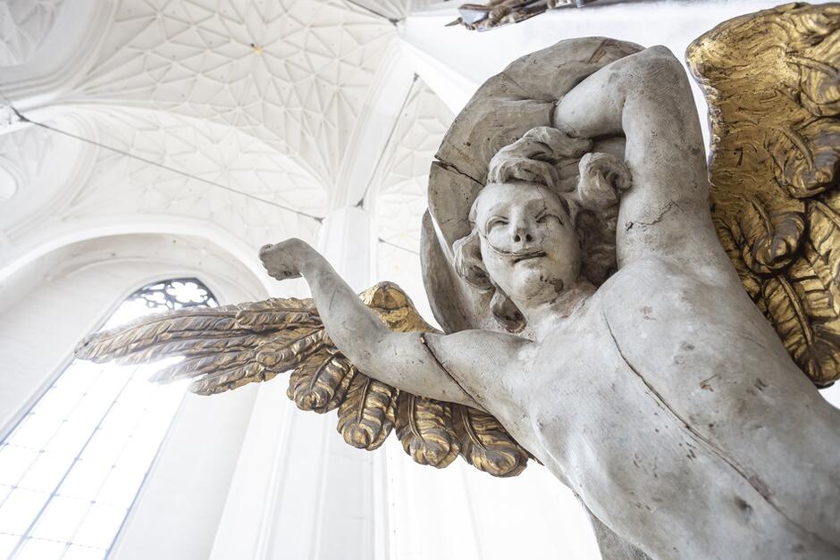 rzeźba anioła przytwierdzona do kościelnego filara, w tle sklepienia bazyliki