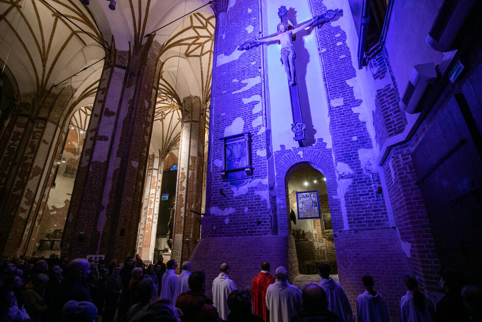 ogromne ciemne gotyckie wnętrze podświetlone na fioletowo, widać postaci chodzące po świątyni