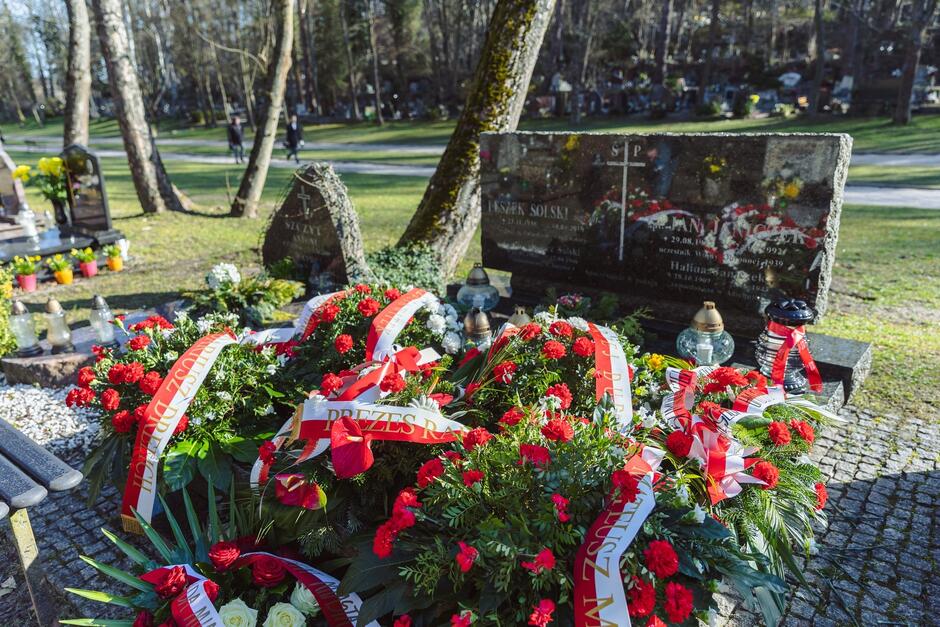 Nagrobek, nami kwiaty i biało-czerwone szarfy