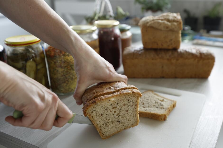 ręce krojące bochenek chleba