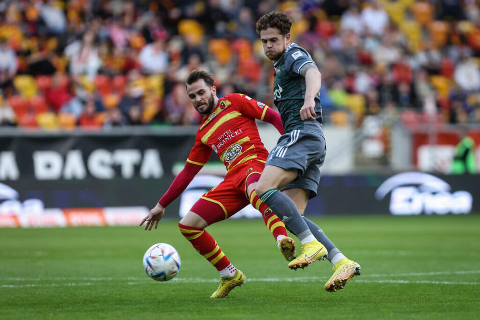 Dwóch piłkarzy - w czerwonym i szarym stroju - walczy o piłkę 