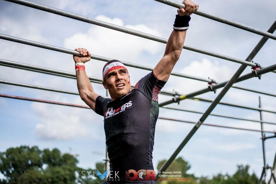 mężczyzna w sportowym stroju, wspina się po poręczach