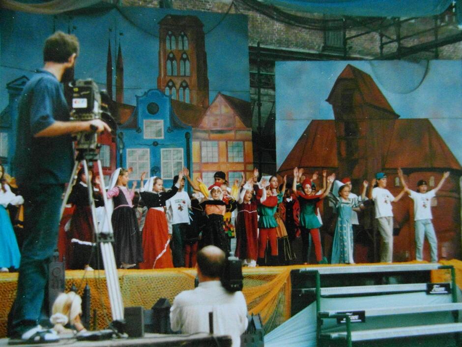 Dzieci na scenie z przedstawieniem, scenografia przedstawia zabytki Gdańska 