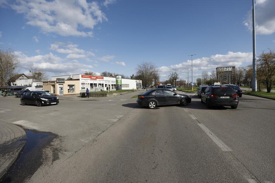 na zdjęciu fragment ulicy, widać samochód stojący w poprzek jezdni próbujący włączyć się do ruchu, przed nim stoi kilka samochodów