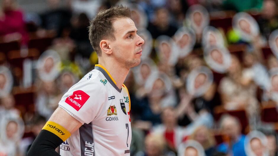 Siatkarz stoi bokiem i patrzy przed siebie