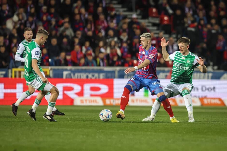 O piłkę na boisku walczy trzech piłkarzy w biało-zielonych strojach Lechii i jeden w granatowo-czerwonym stroju Rakowa 