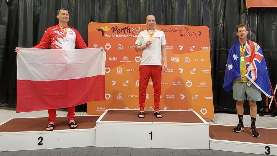 Trzech mężczyzn stoi na stopniach podium