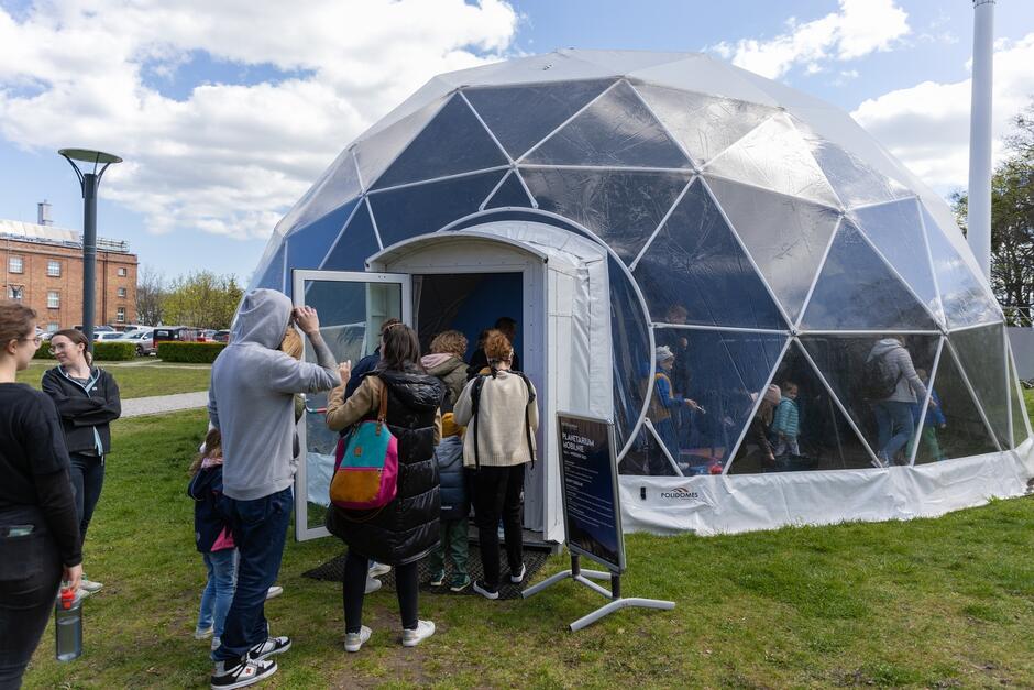 ludzie wchodzą do półkolistego namiotu, w którym jest planetarium