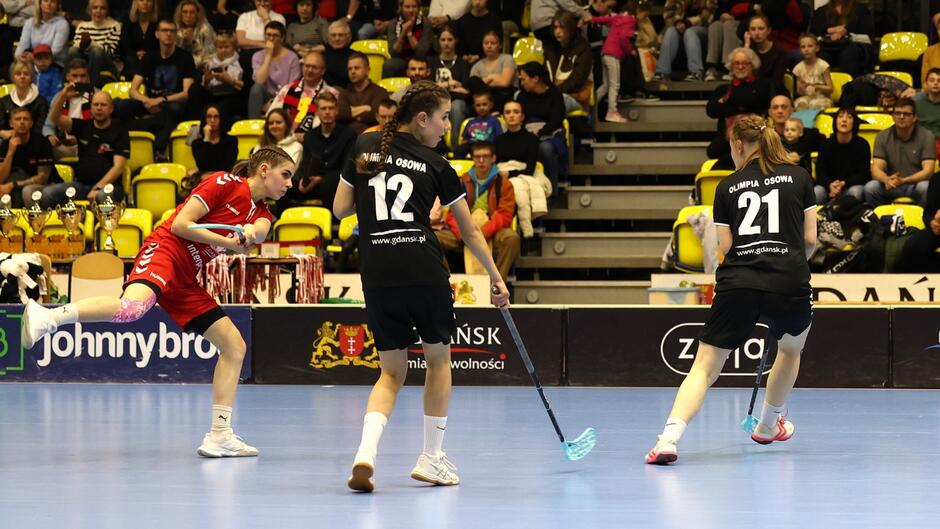 Zawodniczki z kijami na parkiecie. W tle trybuny z widzami