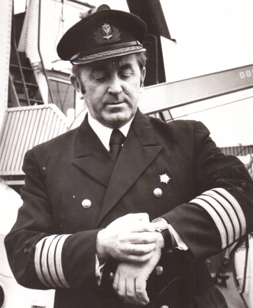 Mężczyzna w mundurze kapitana marynarki handlowej, na statku, spogląda na zegarek
