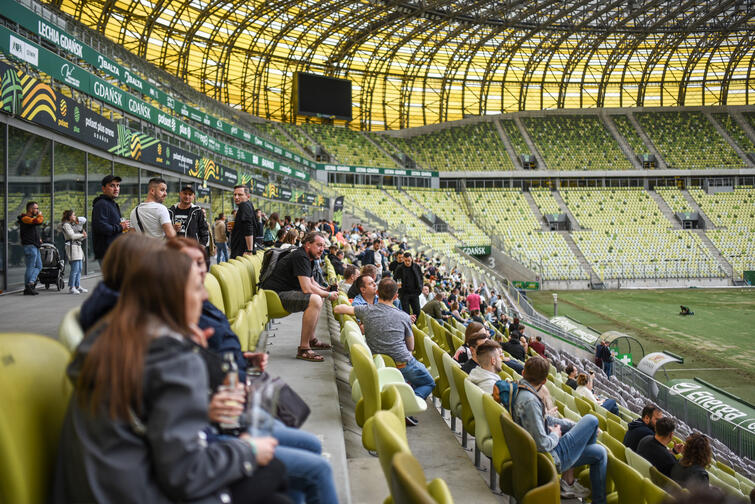 ludzie siedzący na trybunach na stadionie z zieloną murawą