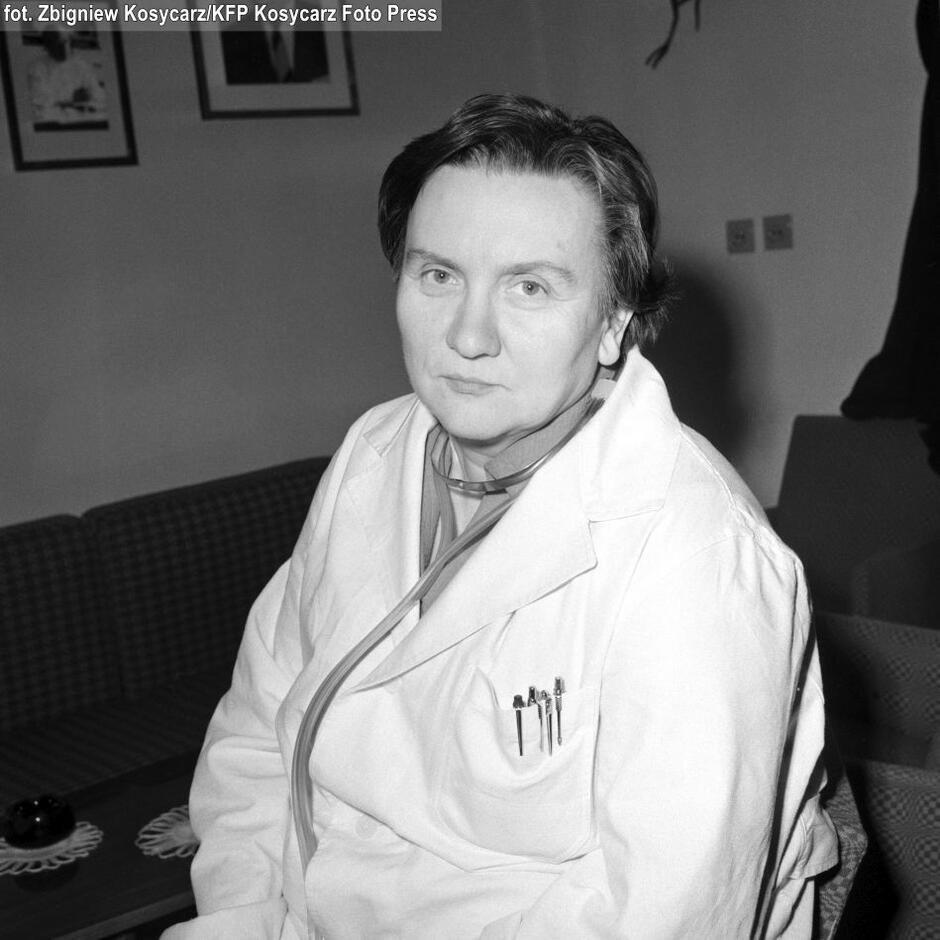 archiwalne foto - kobieta w średnim wieku, w białym kitlu z przewieszony stetoskopem siedzi przy stoliku