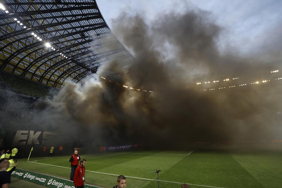 Kłęby czarnego dymu nad murawą i trybunami stadionu