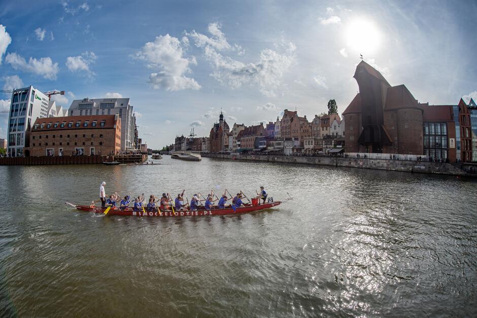 Widok na Motławę i panoramę Gdańska, po której płynie łódź wiosłowa