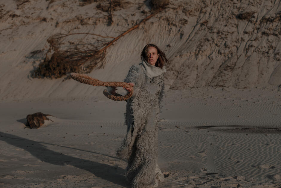 zdjęcie artystyczne, kobieta w oryginalnej długiej sukni pozuje na plaży