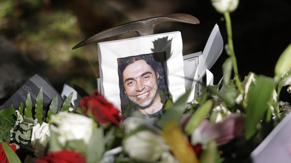 Zdjęcie na grobie wśród kwiatów uśmiechniętego, młodego mężczyzny 