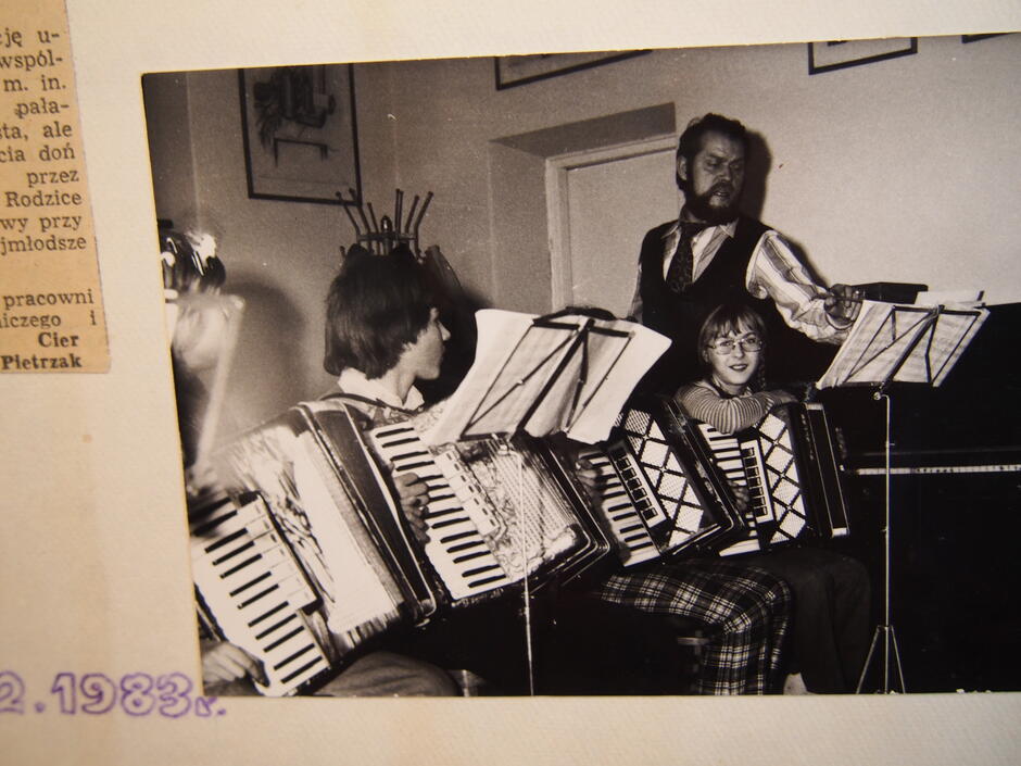 czarno-białe zdjęcie, uczniowie siedzą z akordeonami, przy nich nauczyciel