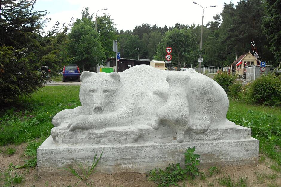 Dużych gabarytów pomnik w kolorze białym - przedstawia leżącą niedźwiedzicę, na którą wspina się młody miś