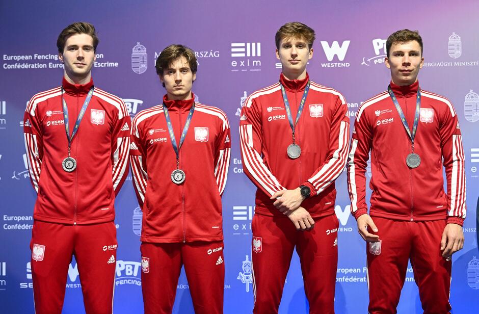 Czterech młodych mężczyzn w czerwonych dresach stoi obok siebie