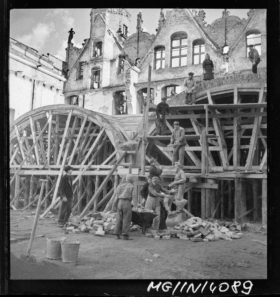 Negatyw czarno-biały ukazuje robotników podczas odbudowy sklepień Wielkiej Zbrojowni w Gdańsku