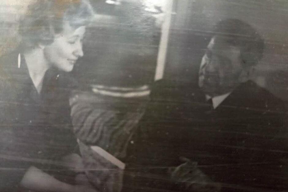 Nieostre czarno-białe zdjęcie przedstawiające młodą kobietą rozmawiającą z mężczyzną