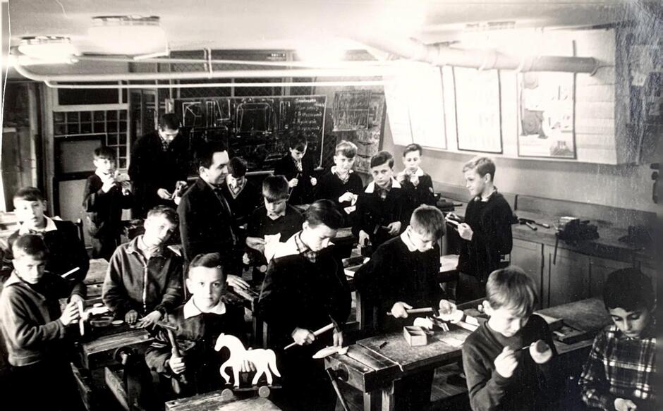 Czarno-białe zdjęcie przedstawiające uczniów w klasie wraz z nauczycielem