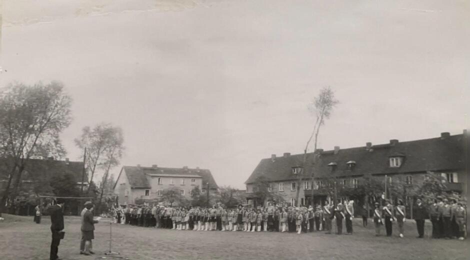 Czarno-białe zdjęcie przedstawiające apel szkolny na boisku