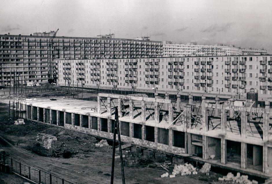 Czarno-białe zdjęcie przedstawiające budowę szkoły wokół bloków mieszkalnych