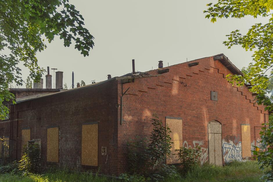 na zdjęciu zabytkowy ceglany budynek, widać płyty pilśniowe wstawione w miejscu okien