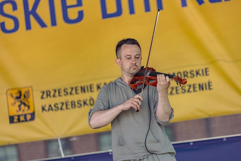 mężczyzna gra na skrzypcach, żółte tło