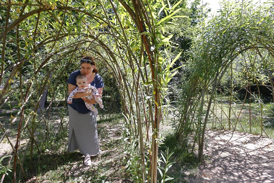 matka z półrocznym dzieckiem na rękach chowa się pod gałęziami opisywanego placu