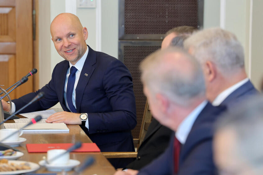 uśmiechnięty łysy mężczyzna w garniturze mówi do mikrofonu