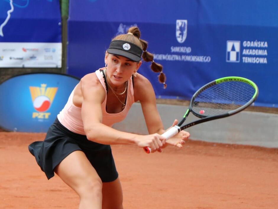 Kobieta na korcie z rakietą w ręku robi zamach