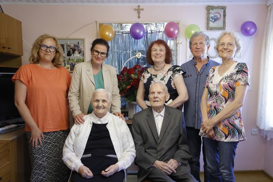 zdjęcie zbiorowe, para seniorów siedzi, za nimi stoją członkowie rodziny i prezydent