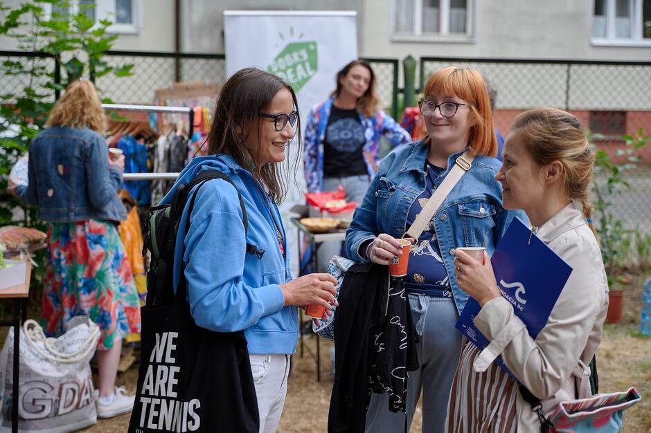 kobiety stoją w kółku i rozmawiają, wokół stoją inni ludzie 
