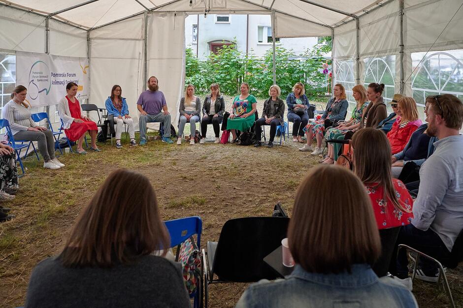 ludzie siedzą w dużym namiocie, w dużym kręgu kilkadziesiąt osób