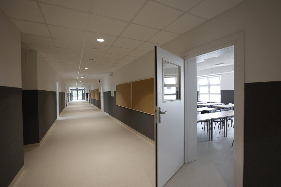 na zdjęciu szkolny korytarz, po prawej uchylone drzwi przez które widać fragment sali lekcyjnej