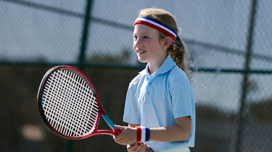 dziewczynka z rakietą tenisową w dłoni, gra na korcie