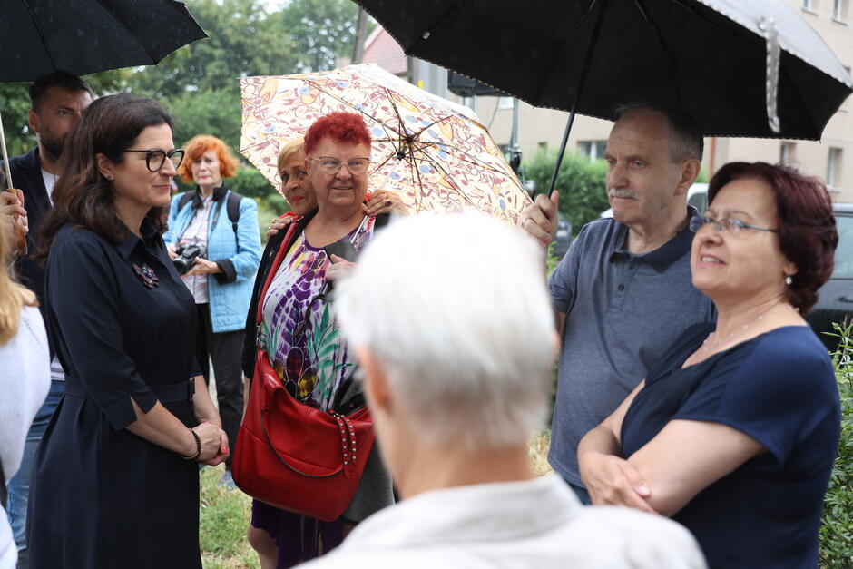 na zdjęciu grupa osób w starszym wieku, rozmawiają ze sobą, kilka osób trzyma parasole