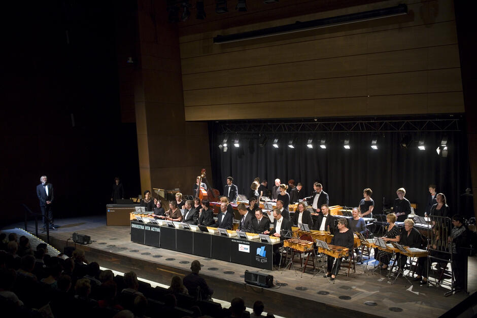 zdjęcie z góry sali na scenę znajdującą się w dole, na niej kilkudziesięciu muzyków