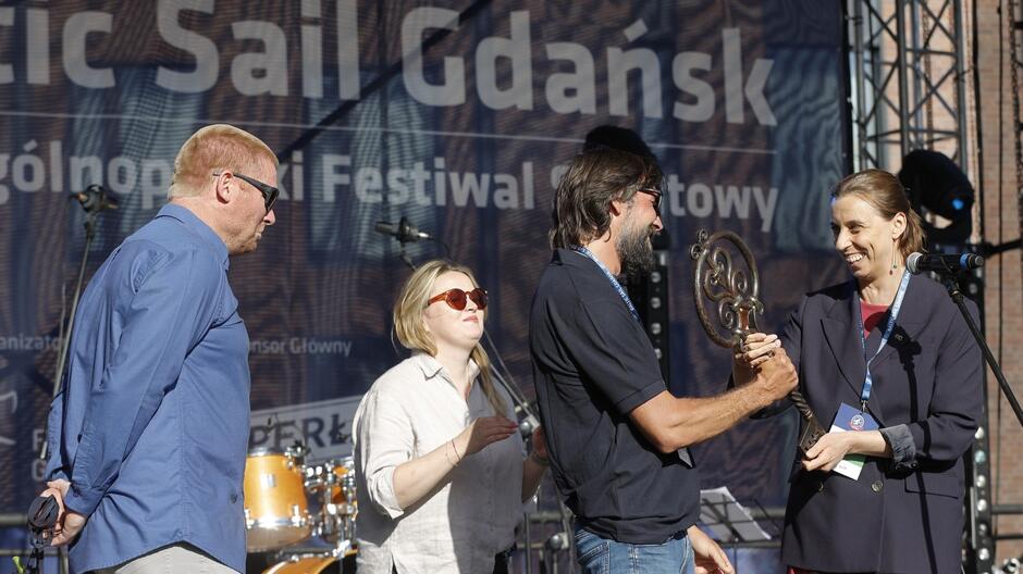 Kobieta wręcza mężczyźnie symboliczne klucze do miasta na tle napisu Baltic Sail