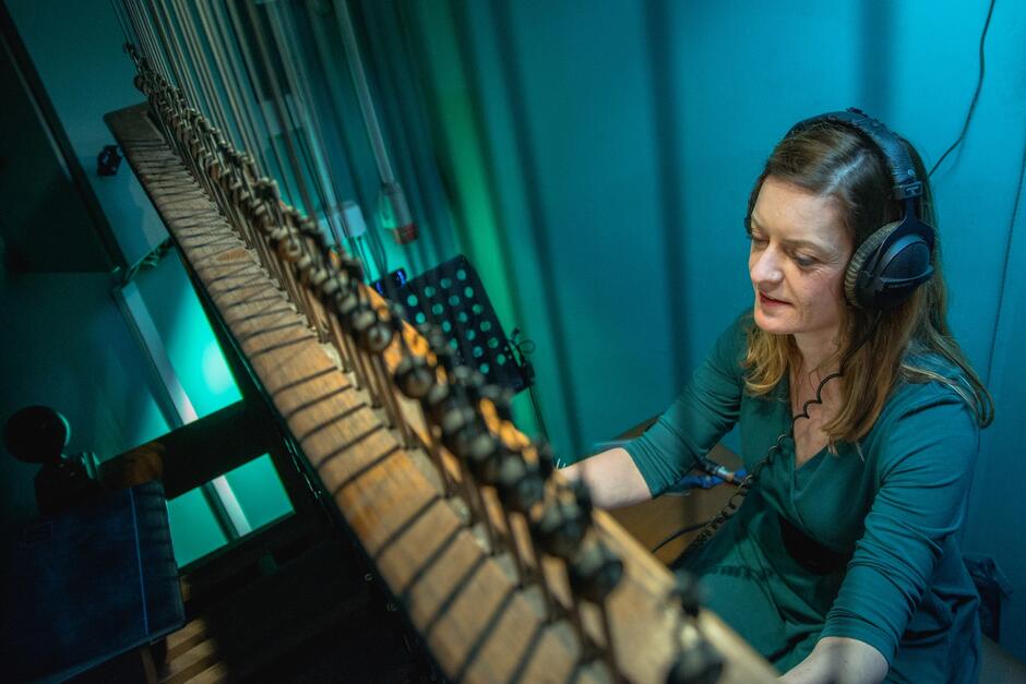 Kobieta w słuchawkach na uszach uderzające w drewniane klawisze instrumentu