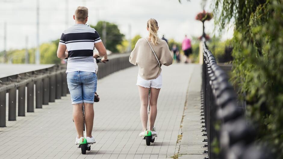 Dwie osoby jadące na hulajnodze