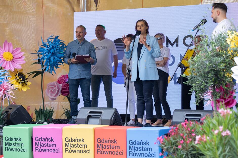 Kobieta przemawiająca na scenie pośród kilku osób, na scenie napis "Gdańsk miastem równości"