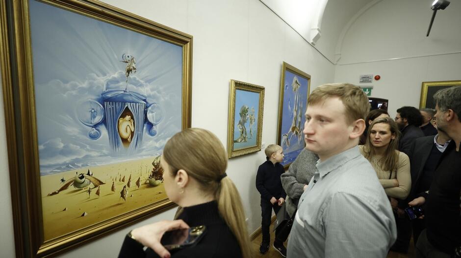 Kilka osób w sali muzealnej patrzących na obrazy