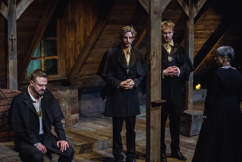 aktorzy na scenie - cztery osoby w czarnych strojach, na strychu