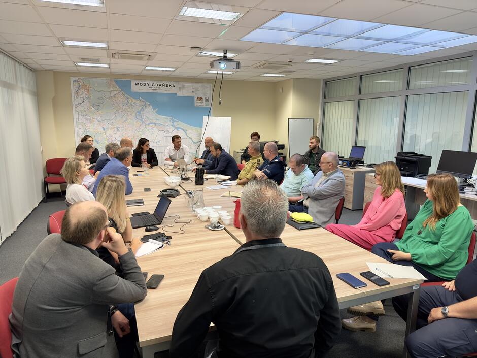 przy długim stole siedzi ponad dwadzieścia osób, rozmawiają