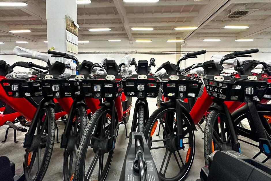 Kilkadziesiąt rowerów w hali, stoją jeden obok drugiego, zdjęcie pokazuje je od produ
