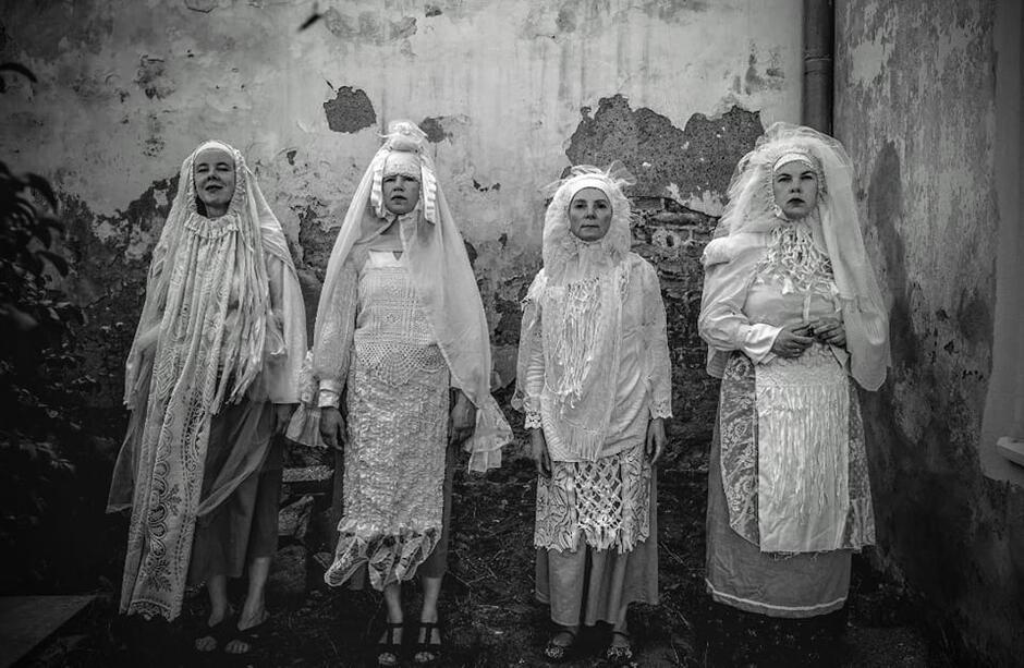 cztery kobiety w białych szatach, długich szatach i chustach na głowie
