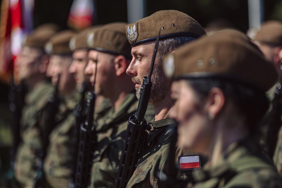 na zdjęciu kilku żołnierzy w beretach i z bronią w ręku, stoi w szeregu